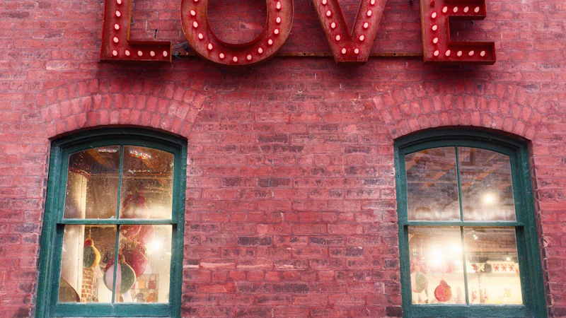Giant red marquee LOVE letters glowing against a brick wall at dusk